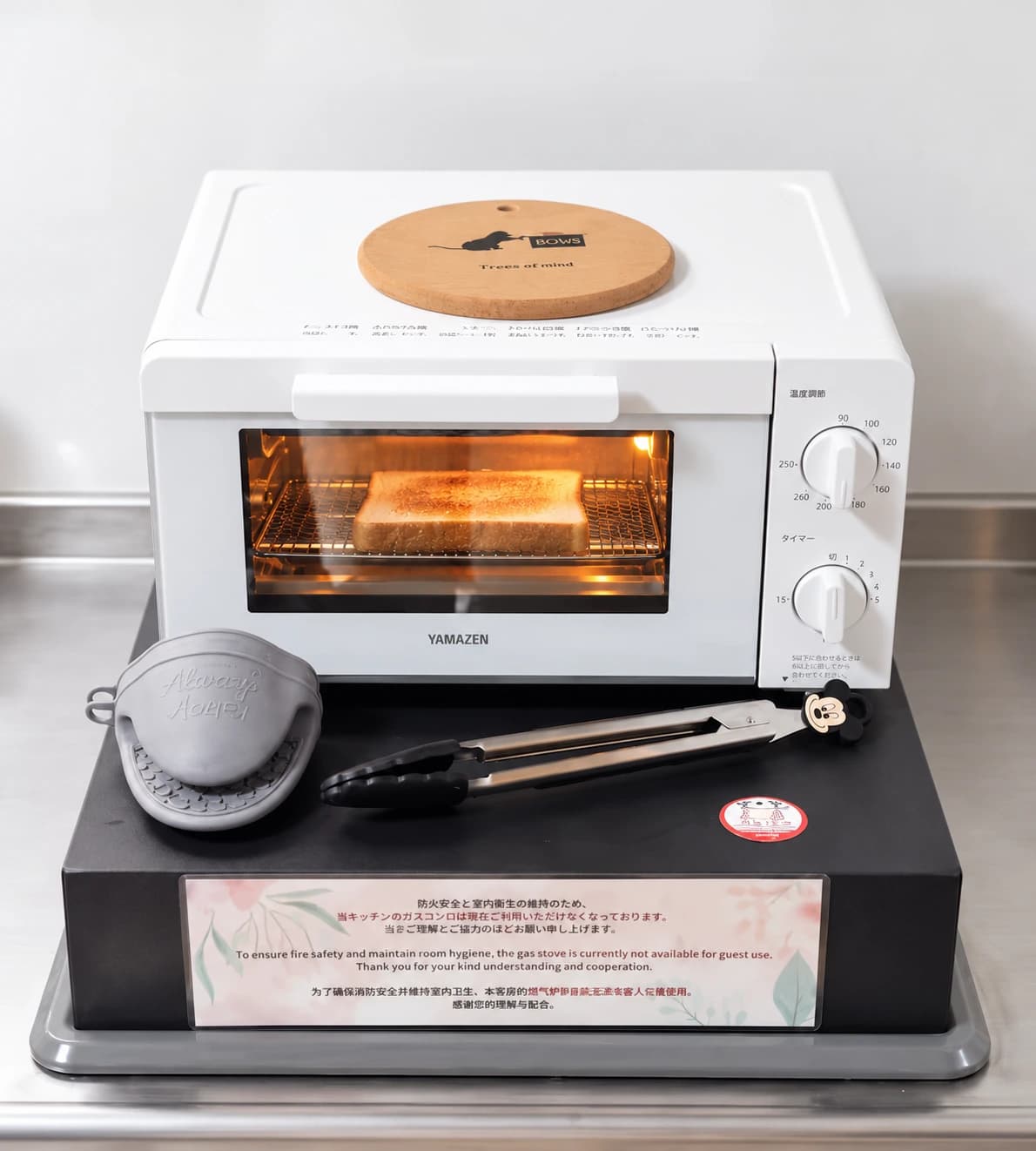 Countertop oven in the MEME Hotel Tokyo kitchenette, above a covered gas stove with a notice prohibiting guest use