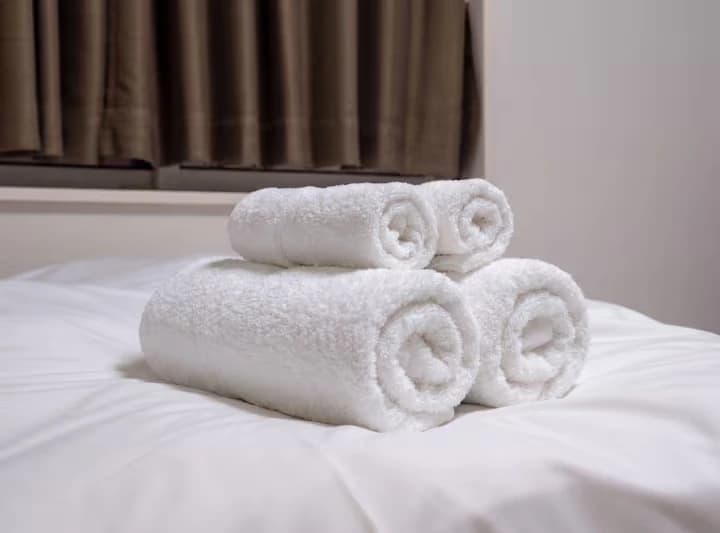 Fresh white bath towels and face towels arranged on a guest bed at MEME Hotel Tokyo